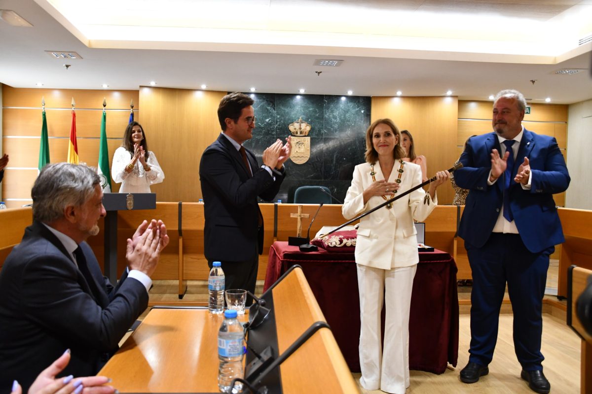 Julia Ibáñez sostiene el bastón de Alcaldía, junto a Francisco Góngora y José Francisco Rivera, entre el aplauso de la corporación y público